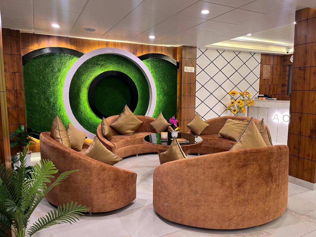 a lobby with brown couches and a green wall at Accom Hotel in Ilām