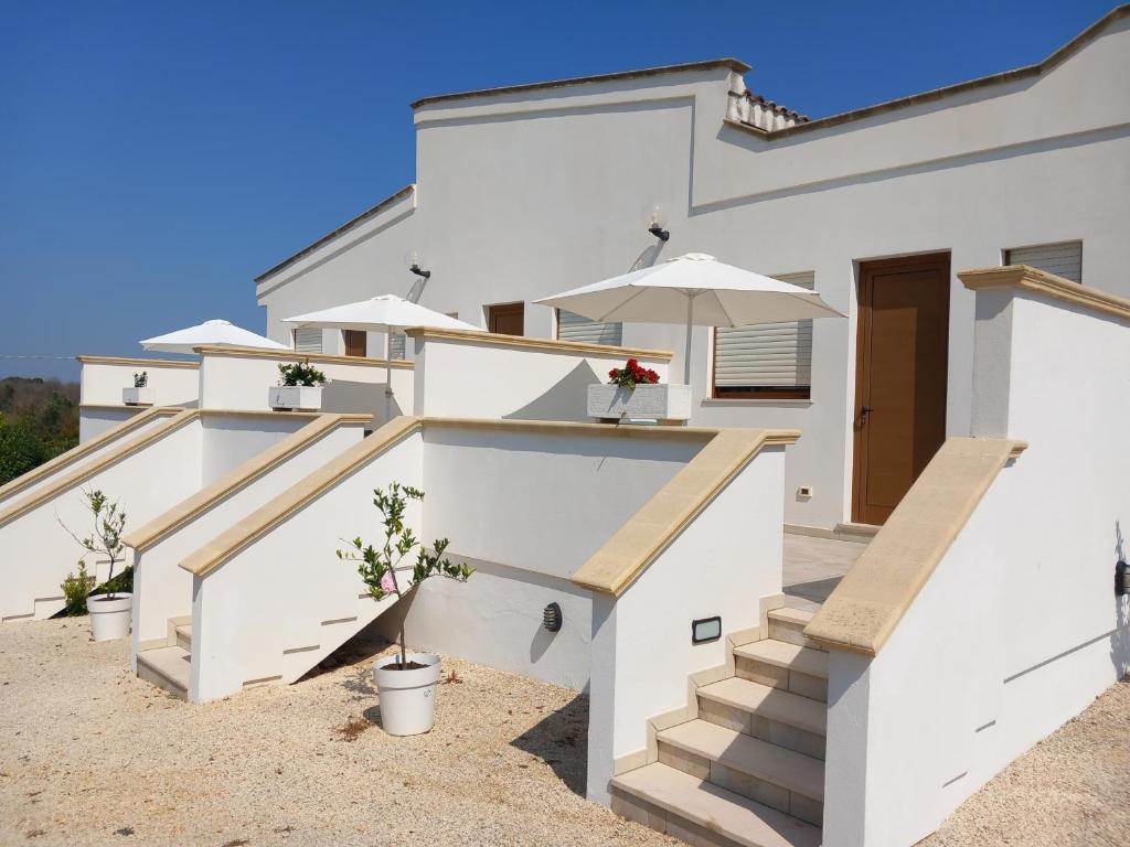 una casa bianca con scale e ombrellone di Agriturismo Terra dei Profumi a Otranto