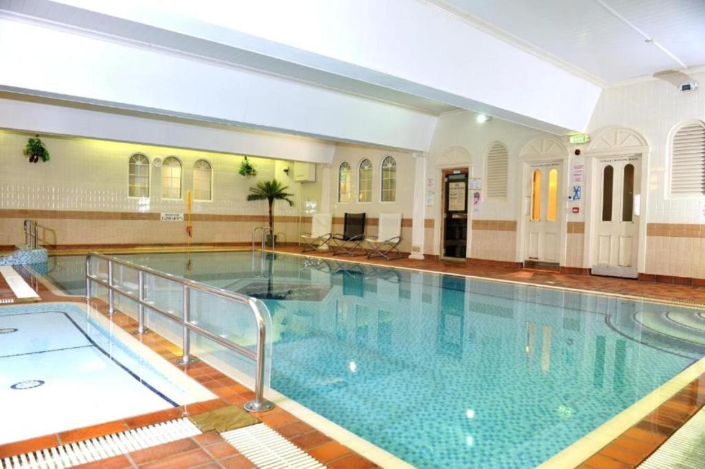 ein großer Pool in einem Gebäude in der Unterkunft Queens Hotel & Spa Bournemouth in Bournemouth