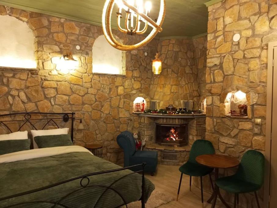 a bedroom with a stone wall with a bed and a fireplace at Anneta s StudioBear s Path in Sklíthron