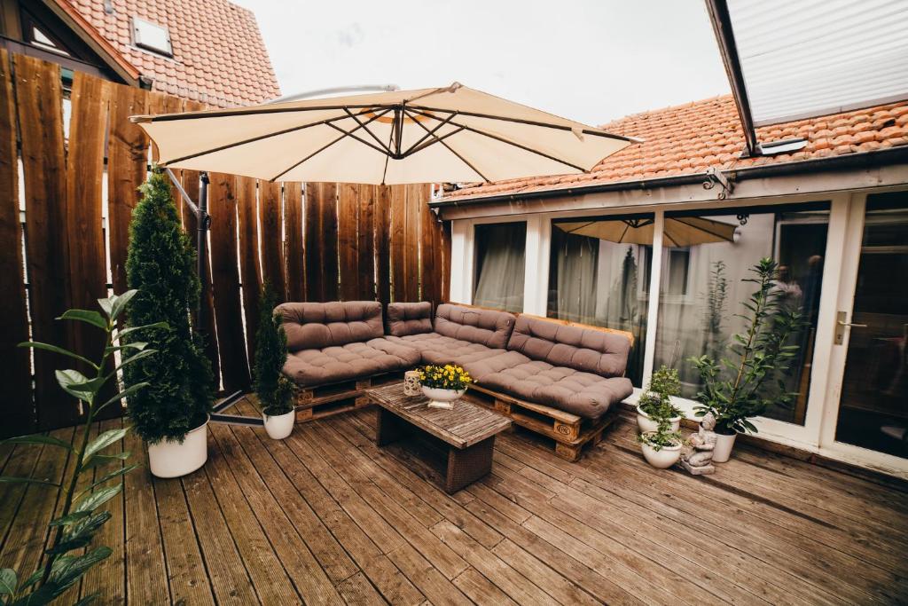 a patio with a couch and an umbrella on a deck at NEW人 Dachterrasse PRIME/TV 人 4min zum Bhf in Kornwestheim