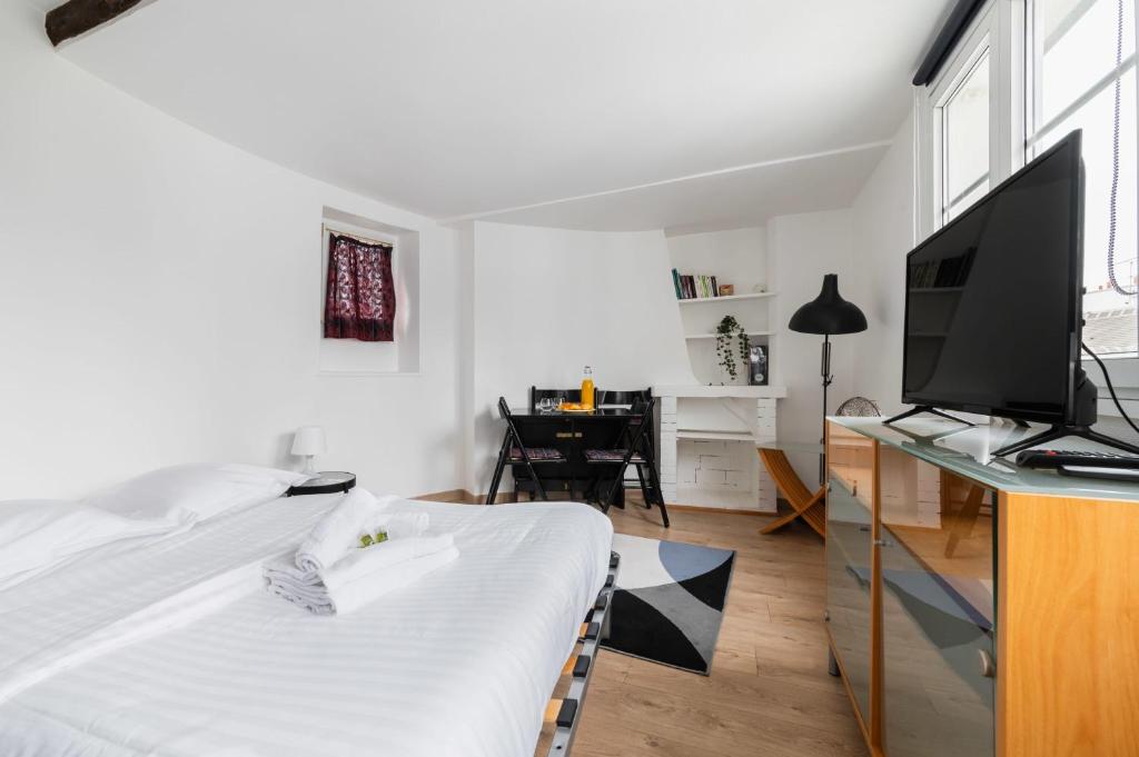 a bedroom with a bed and a desk with a television at Agréable studio cœur de paris - Paris 6 - 2P in Paris