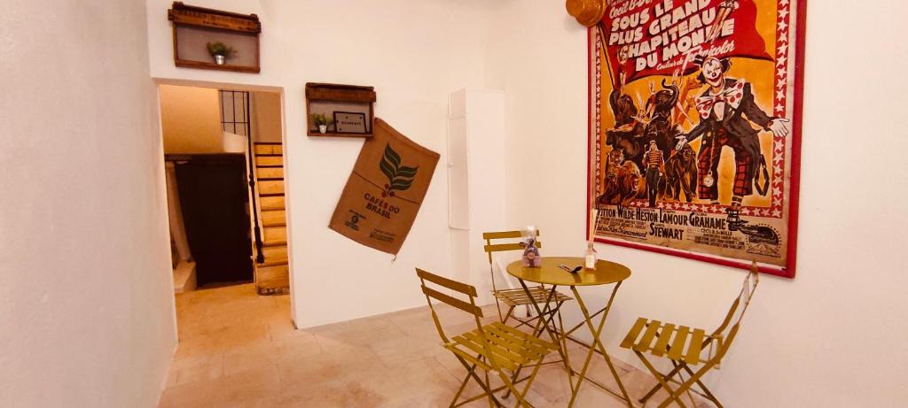 a room with a table and chairs and a poster on the wall at LOUSTERAPH in Saint-Rémy-de-Provence