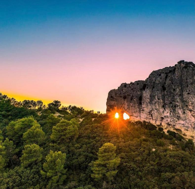 une image du soleil se couchant derrière une montagne dans l'établissement LOUSTERAPH, à Saint-Rémy-de-Provence