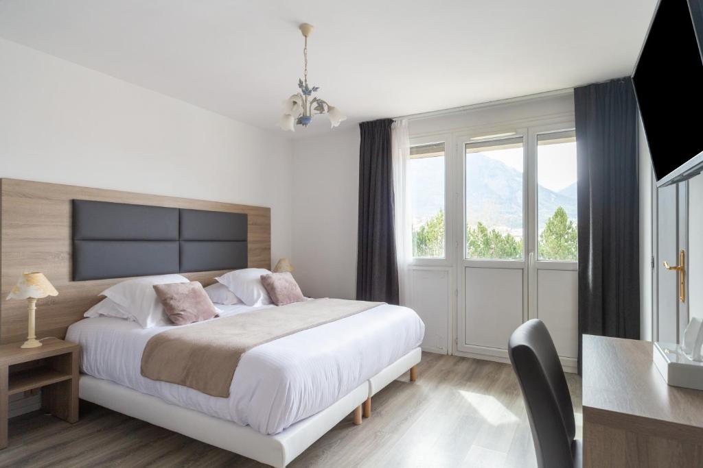 - une chambre avec un lit et une grande fenêtre dans l'établissement Hôtel Vauban Briançon Serre Chevalier, à Briançon