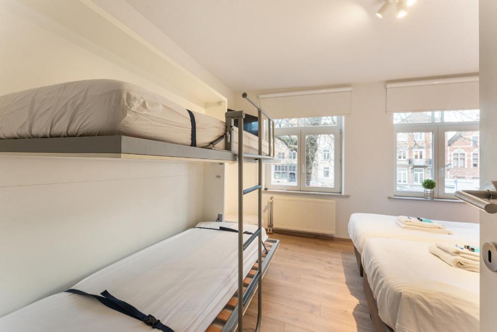 two bunk beds in a room with two windows at Brugse charme huis met tuin aan het water 8p in Bruges