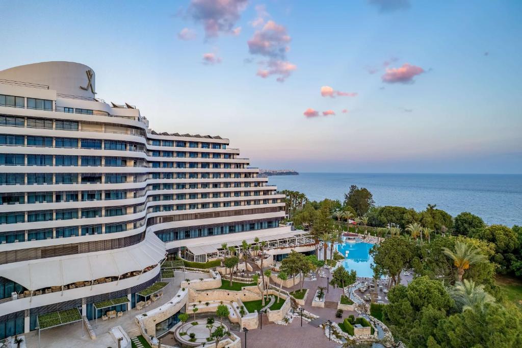 a large building with a pool in front of the ocean at Rixos Downtown Antalya - The Land Of Legends Access in Antalya