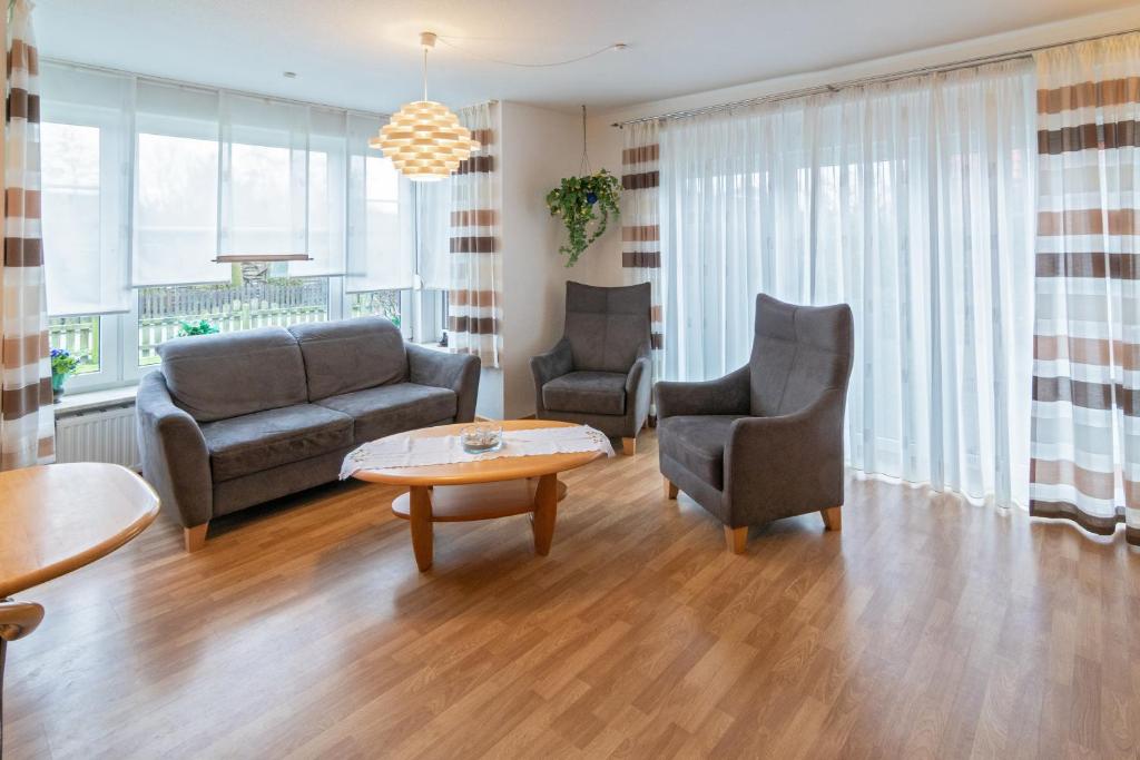 ein Wohnzimmer mit einem Sofa, 2 Stühlen und einem Tisch in der Unterkunft Ferienhaus Sieleck in Dornumersiel