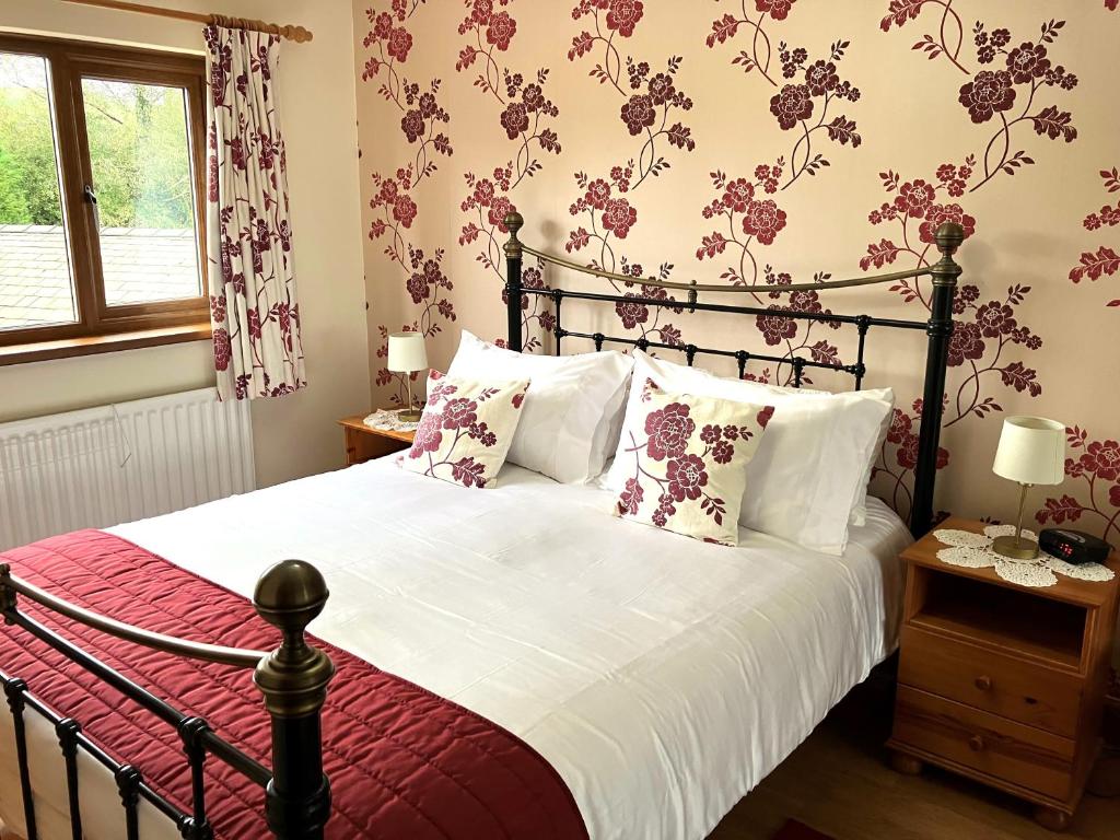 a bedroom with a large bed with flowers on the wall at Emerald Bank Cottage in Uldale