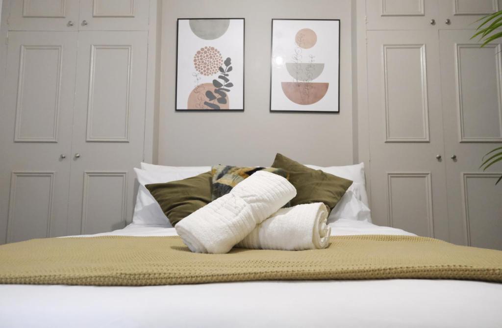 a bed with two rolled up towels on it at Stylish Studio Apartments, Willesden in London