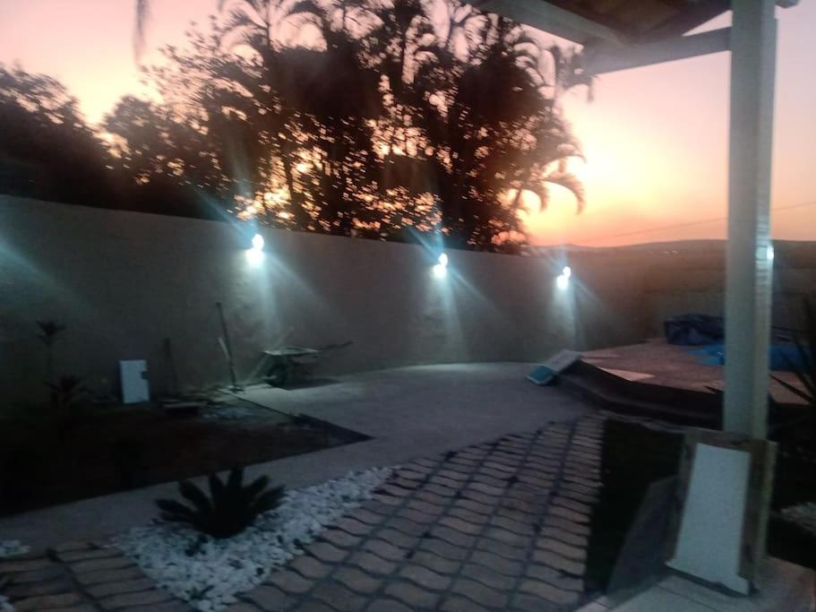 a patio with a palm tree and a wall with lights at Casa de campo agradável com piscina aquecida in Juatuba