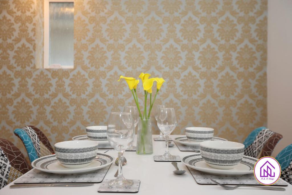 a table with plates and glasses and yellow flowers on it at Hollybush House, Great Location, Free Parking in Cardiff