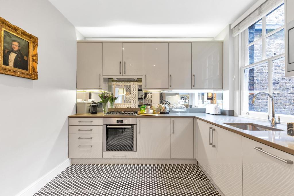 a kitchen with white cabinets and a sink at London Chelsea in London