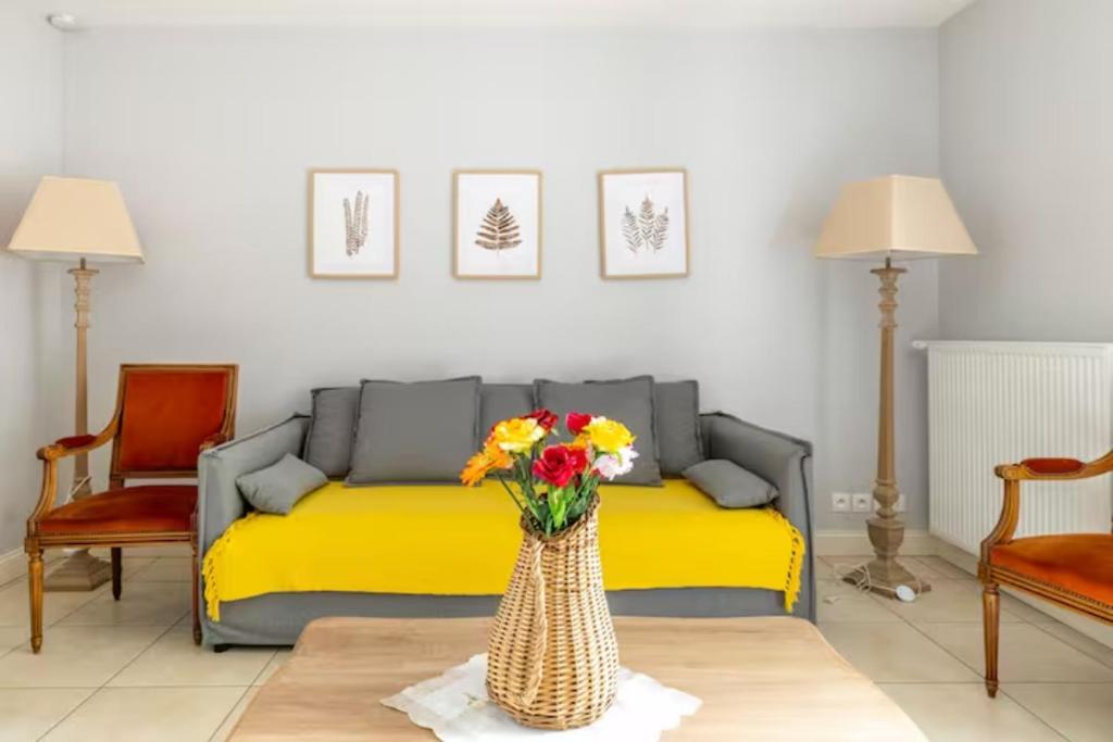 - un salon avec un canapé et un vase fleuri dans l'établissement Domaine de la Garnauderie Gite des Chênes, à Sainte-Maure-de-Touraine