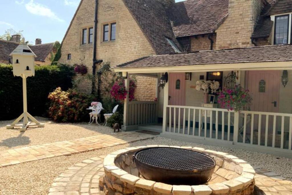 une terrasse avec un foyer extérieur en face d'une maison dans l'établissement Piglet Lodge, à Pebworth