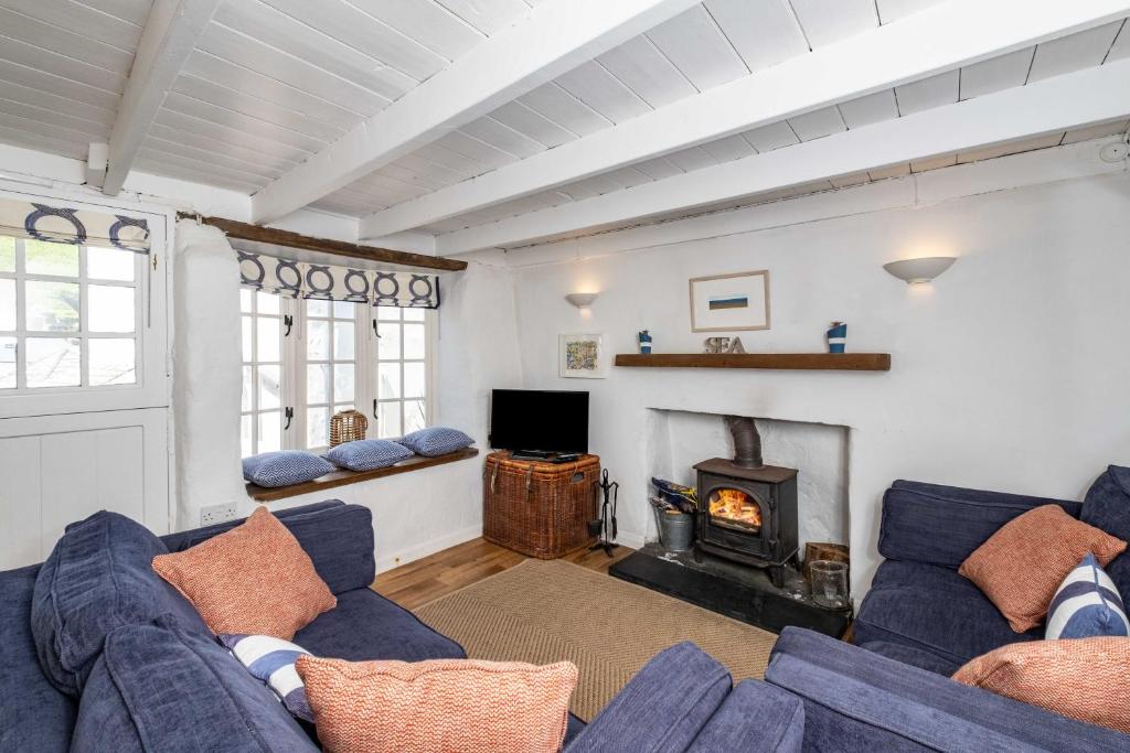 a living room with two blue couches and a fireplace at Sea Horses in Port Isaac