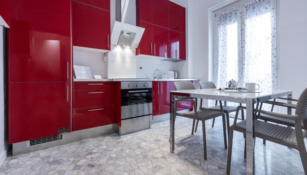 a kitchen with red cabinets and a table with chairs at Italianway Comfort - Merlo 1 D in Milan