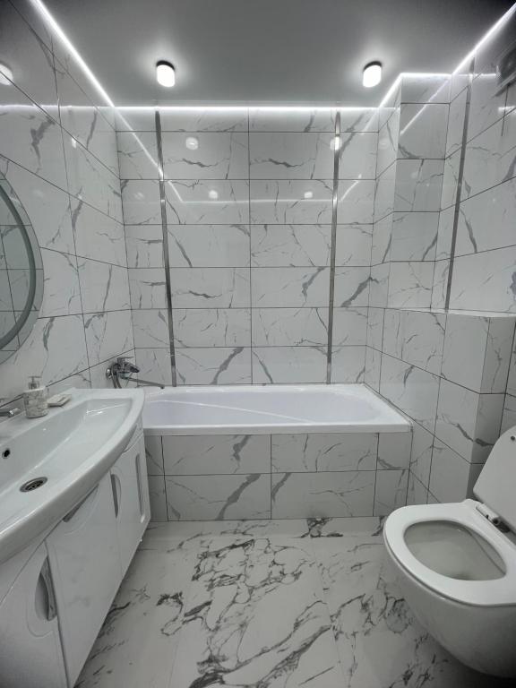 a white bathroom with a tub and a toilet at Яркая студия в новом доме in Oral