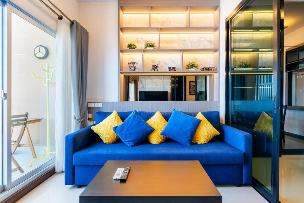 un sofá azul con almohadas amarillas en la sala de estar. en Luxury 31st Top Floor Condo with Swimming Pool, en Chiang Mai