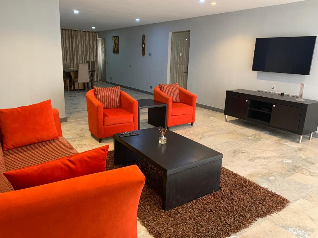 a living room with orange furniture and a flat screen tv at The Emem Apartment Collections in Lagos