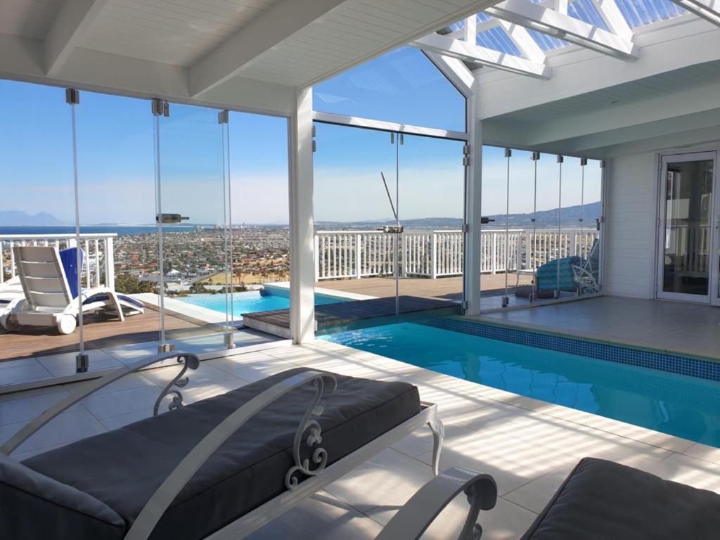 a house with a swimming pool with a view at 'The Bolussi Beachhouse', sleeps 12 in 6 en-suite bedrooms with Indoor Pool in Gordonʼs Bay
