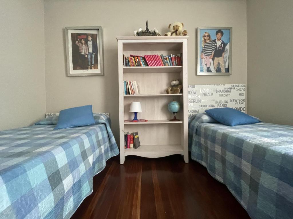 1 dormitorio con 2 camas y estante para libros en Habitación Aeropuerto Loiu, en Loiu