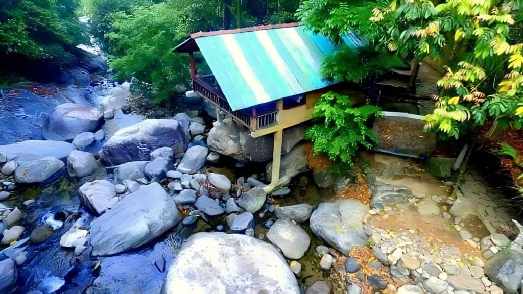 una pequeña casa en medio de un río en Cave N Falls Nature Resort & Water Park, en Kitulgala