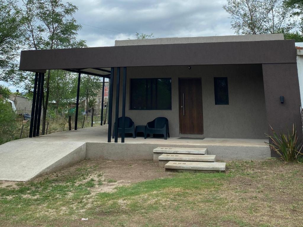 une petite maison avec une terrasse couverte et des chaises en face de celle-ci dans l'établissement Casa Moderna, à Mina Clavero