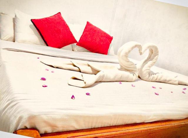 Una cama con dos cisnes hechos para parecer corazones en River Side Cottage, en Udawalawe