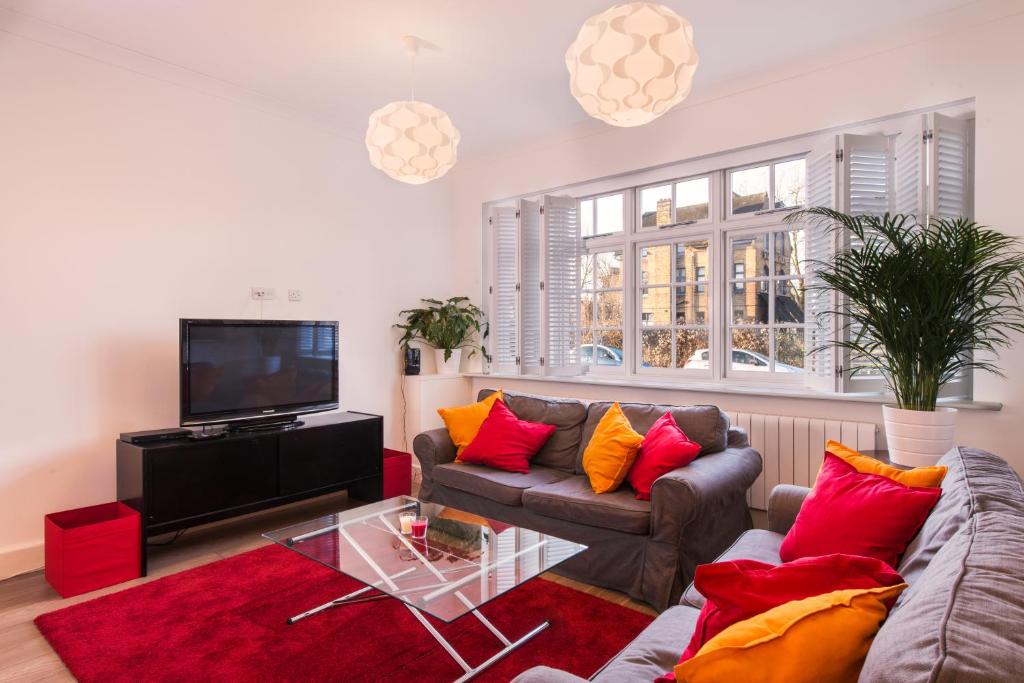 een woonkamer met een bank en een tv bij London House in Londen