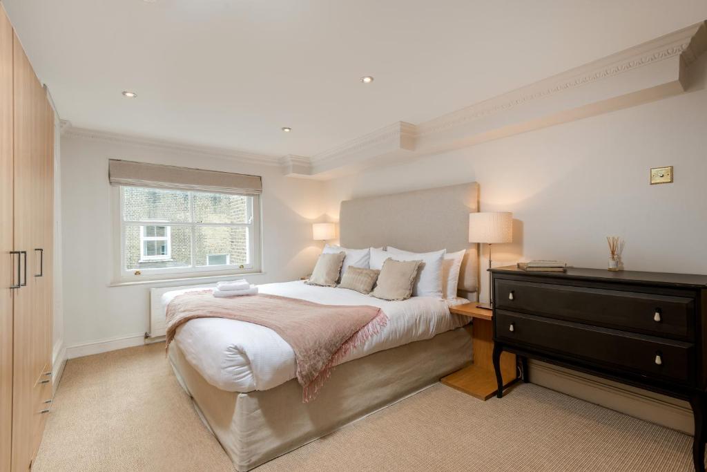 a bedroom with a bed with a dresser and a window at Spacious, Calm One Bedroom in London