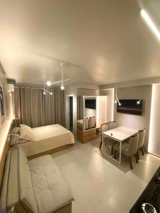 Kitnet alto padrão sem taxa de limpeza في كاشويرا دو سول: غرفة نوم بسرير وطاولة واريكة