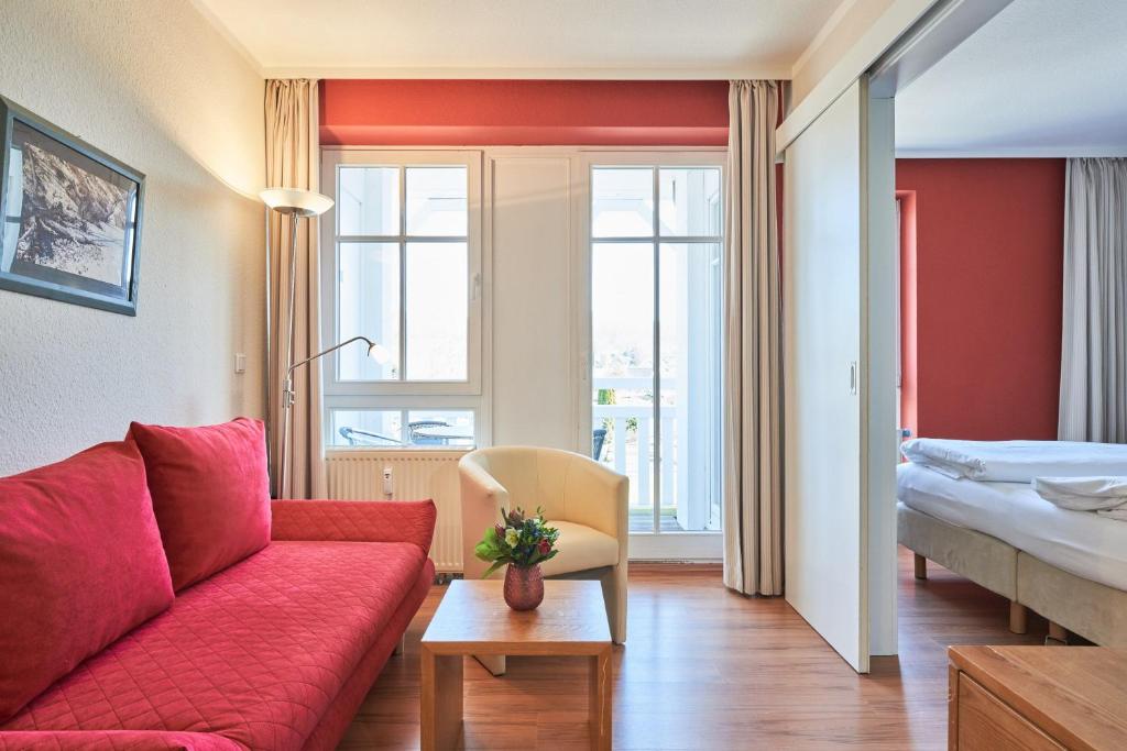 sala de estar con sofá rojo y cama en Fewo 300, Seepark Sellin, en Ostseebad Sellin