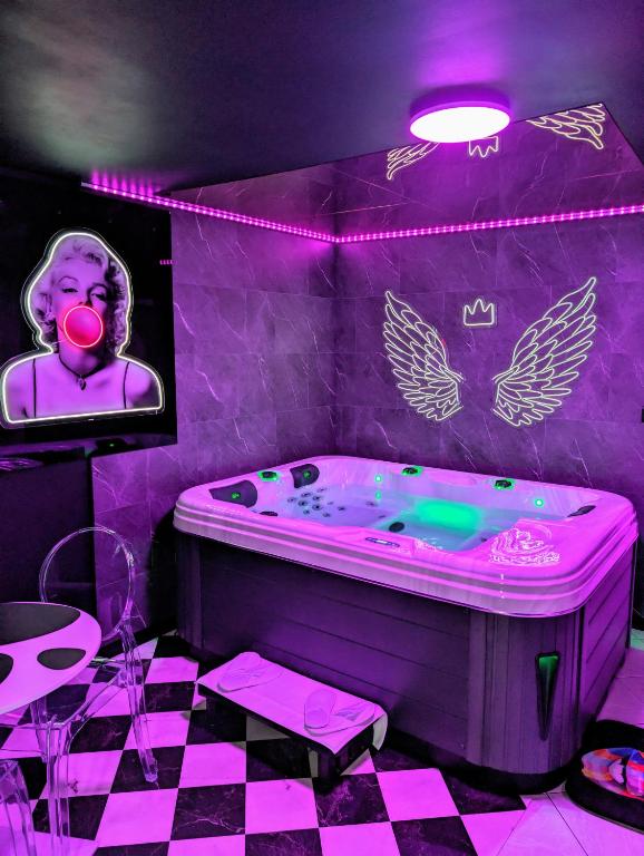 a purple room with a bath tub with a picture of a woman at Le Spacidulé in Saint-Amand-les-Eaux