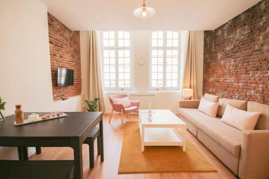 a living room with a couch and a brick wall at Lille Centre - Nice and functional ap. in Lille