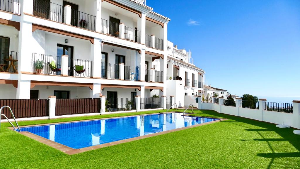 a hotel with a swimming pool in front of a building at Casita Frigiliana - stunning new apartment with views with private parking space in Frigiliana