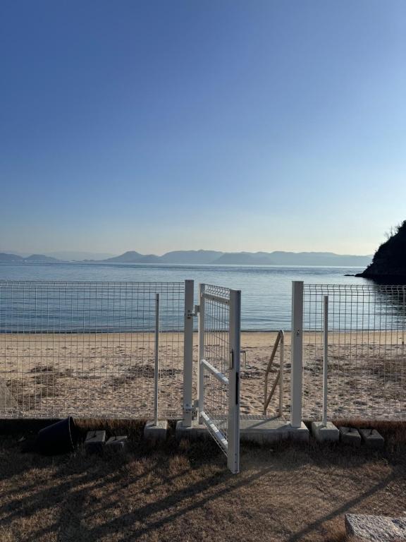 a gate on a beach next to the water at Vacation House YOKOMBO in Naoshima