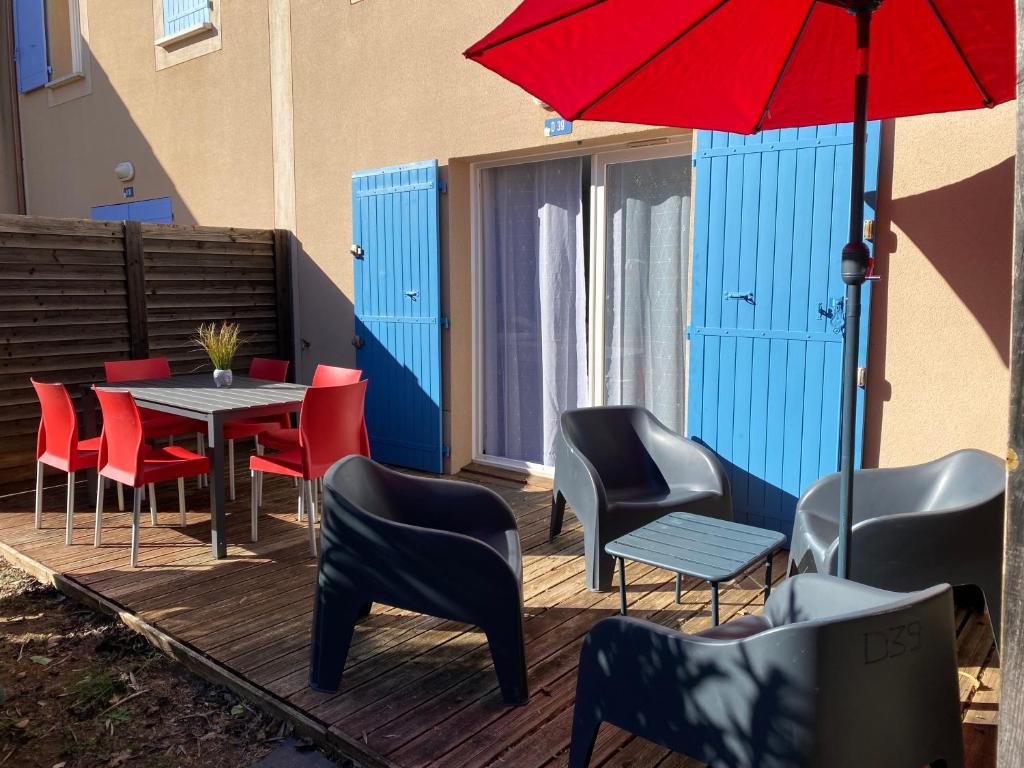 a patio with a table and chairs and a red umbrella at Maison Résidence les demeures du Ventoux in Aubignan
