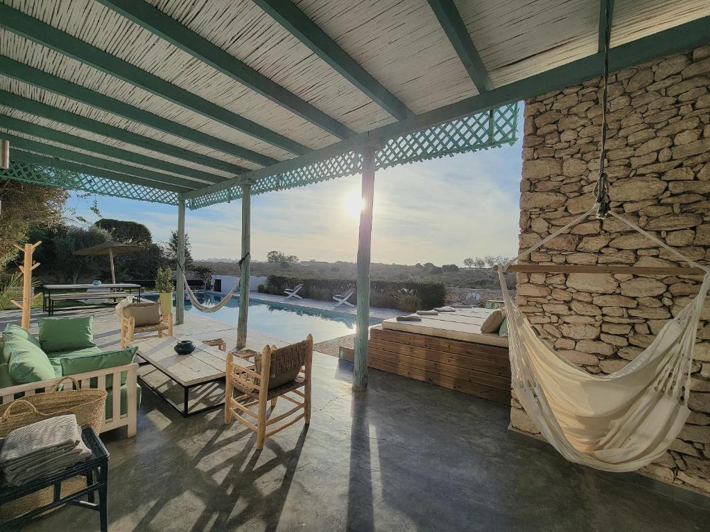 un patio avec un hamac et une piscine dans l'établissement Villa Dar Céleste, à Essaouira