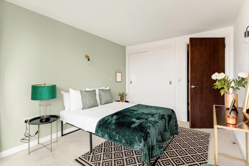 a bedroom with a bed with a green blanket on it at Gorgeous Mile End Flat in London
