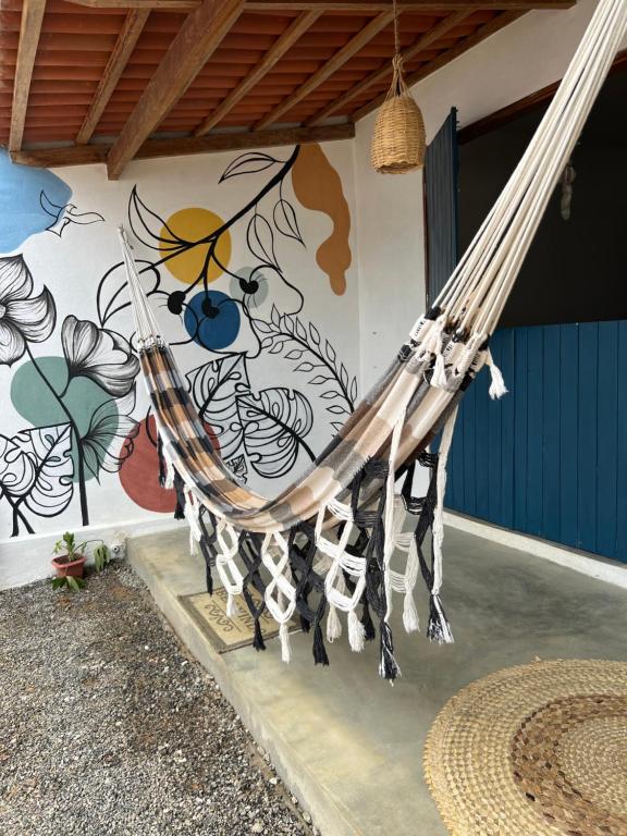 a hammock in front of a wall with a mural at Quarto Sertão no Mar in Barra do Cunhau