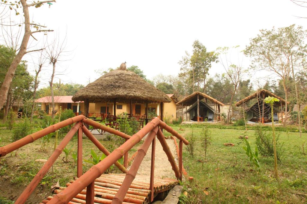 a house with a thatched roof and a bridge in front at Forest Hideaway Resort Pvt Ltd in Bhurkīā