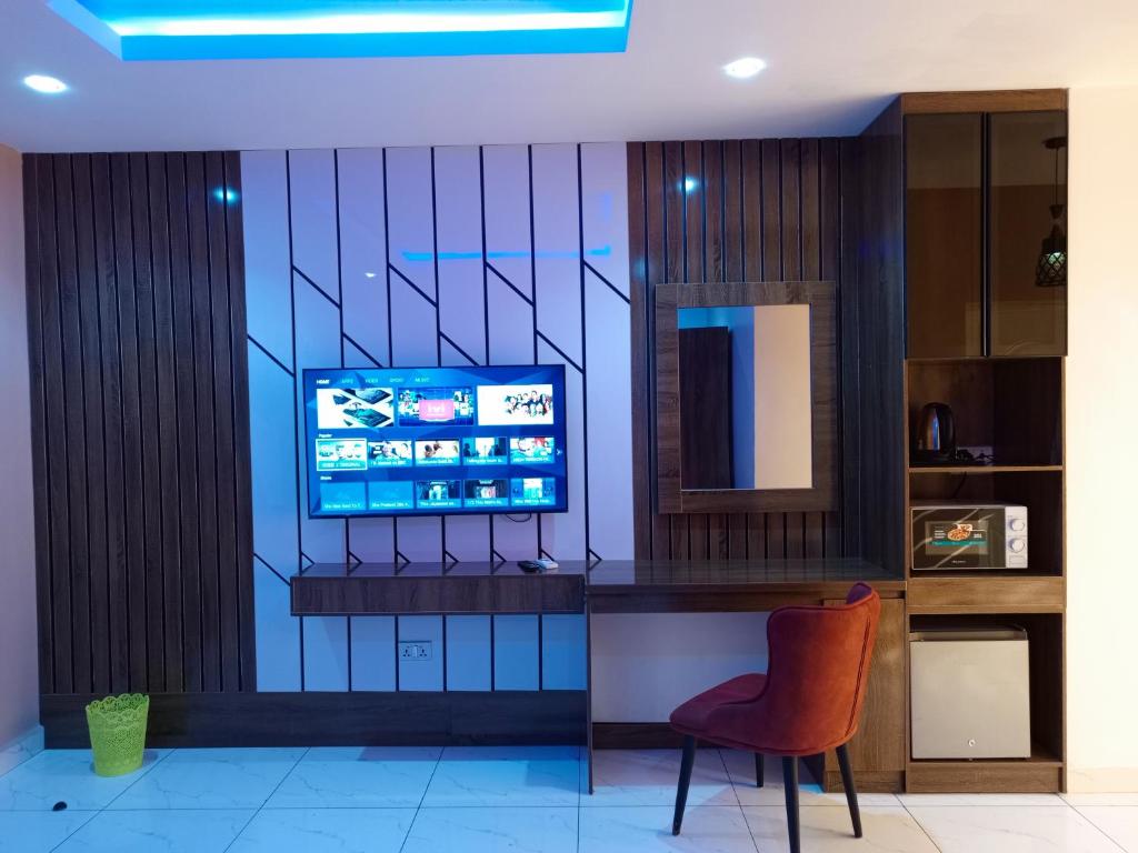 a living room with a television and a chair at The Seasons Apartment Kado in Abuja