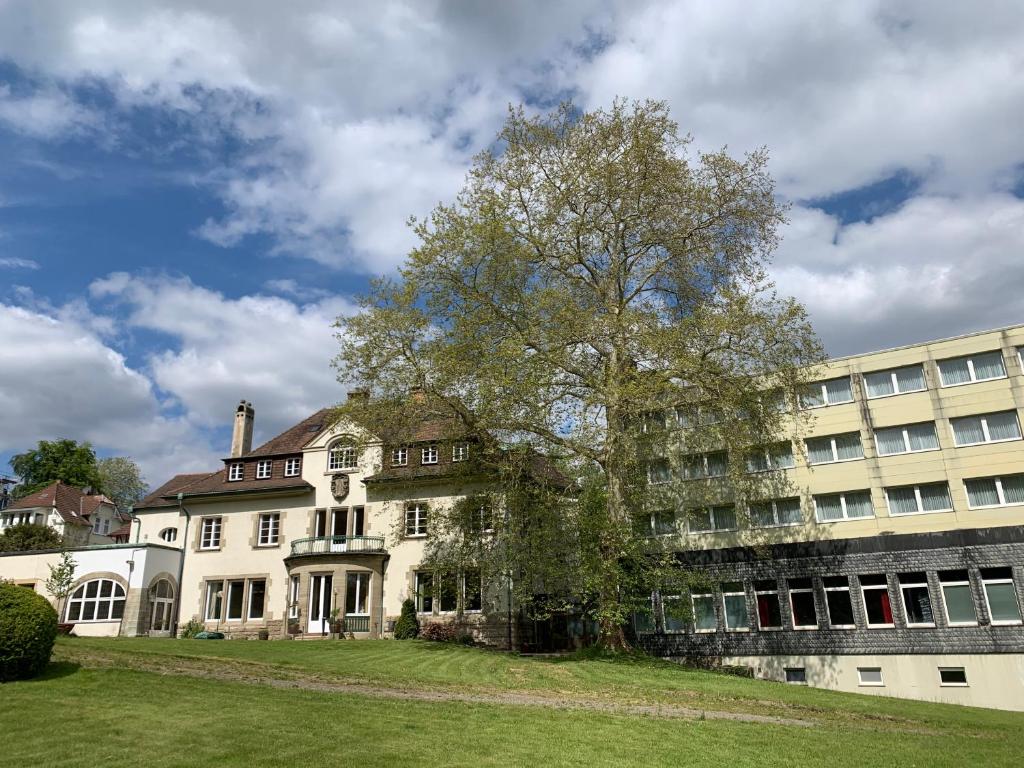 a large white house with a tree in front of a building at ParkHotel Bad Harzburg in Bad Harzburg