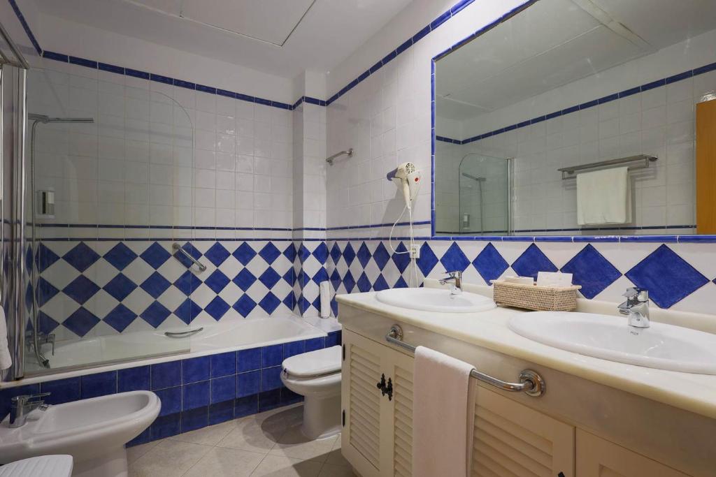 a bathroom with a sink and a toilet and a mirror at Hotel Tugasa Castillo de Castellar in Castellar de la Frontera
