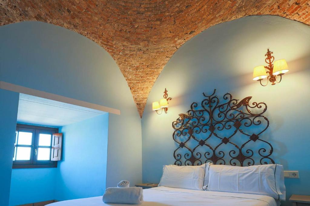 a bedroom with a bed with a blue wall at Hotel Tugasa Castillo de Castellar in Castellar de la Frontera