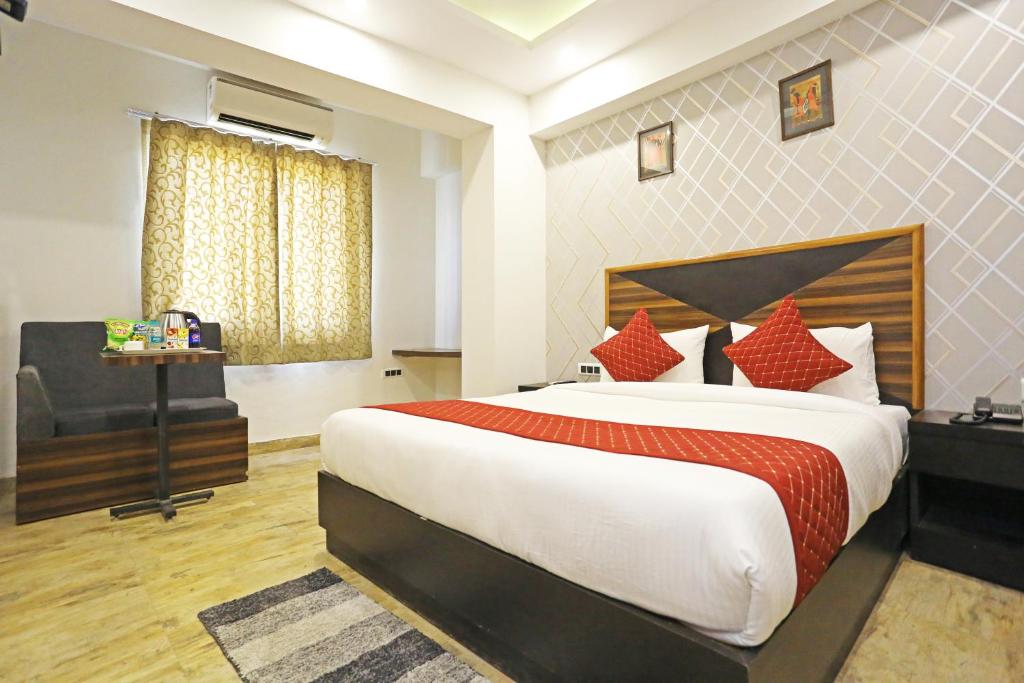 Hotel Gross International near delhi airport في نيودلهي: غرفة نوم بسرير كبير وكرسي
