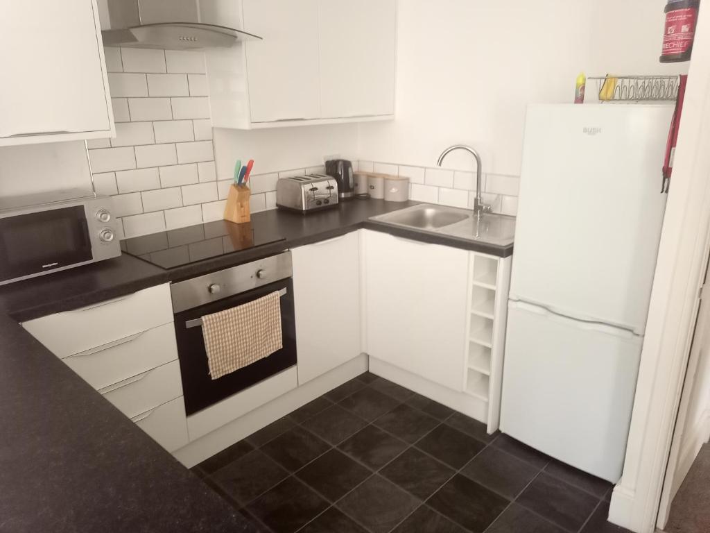 uma cozinha com armários brancos, um lavatório e um frigorífico em Hull City Centre Accommodation 1 em Hull