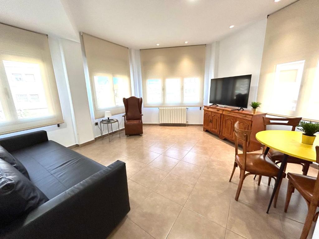 ein Wohnzimmer mit einem Sofa und einem TV in der Unterkunft Torre de Romo - Más que apartamentos in Murcia