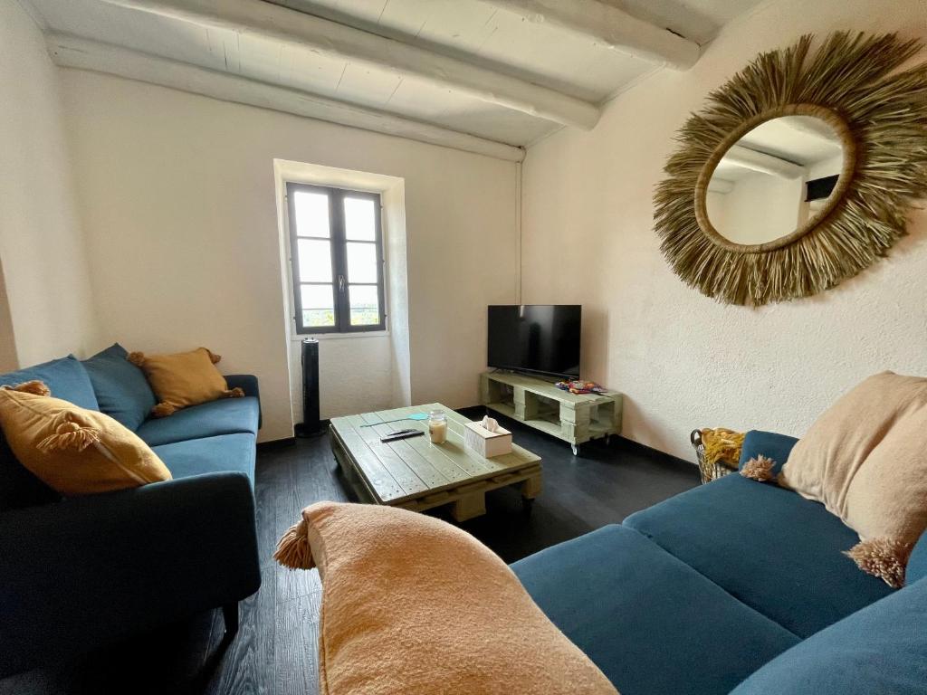 a living room with a blue couch and a mirror at Le Planzollais in Planzolles
